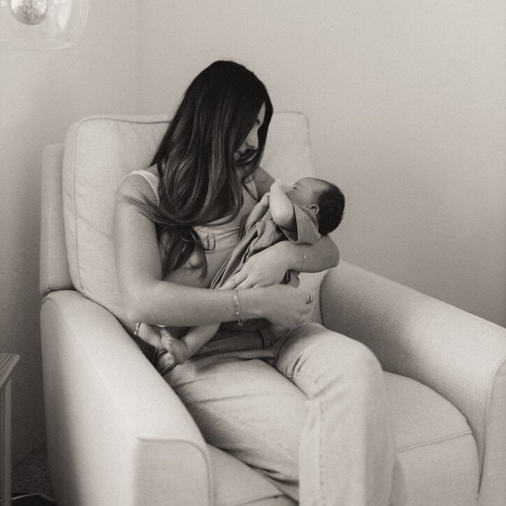 mom sitting in chair with newborn baby postpartum
